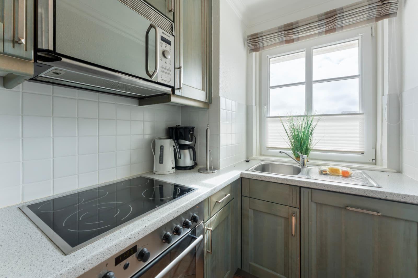 Kitchen with induction cooktop, sink, and window with blinds.