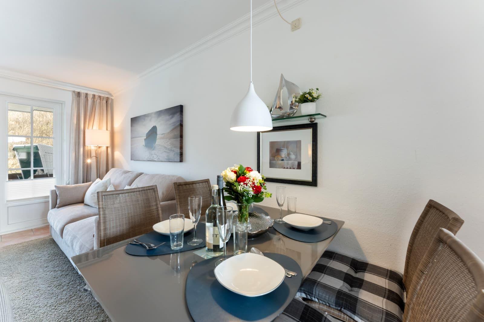 Dining table with chairs and set table. Background: sofa and wall art.