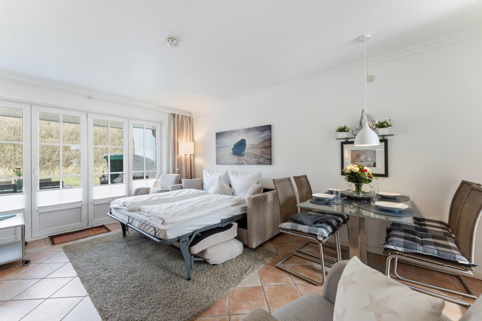 Sleeping room with sofa bed, dining area, and windows to outdoor terrace.