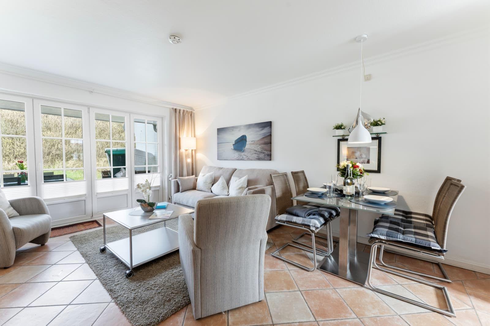 Living and dining area with sofa, table and chairs. Windows to the outside.
