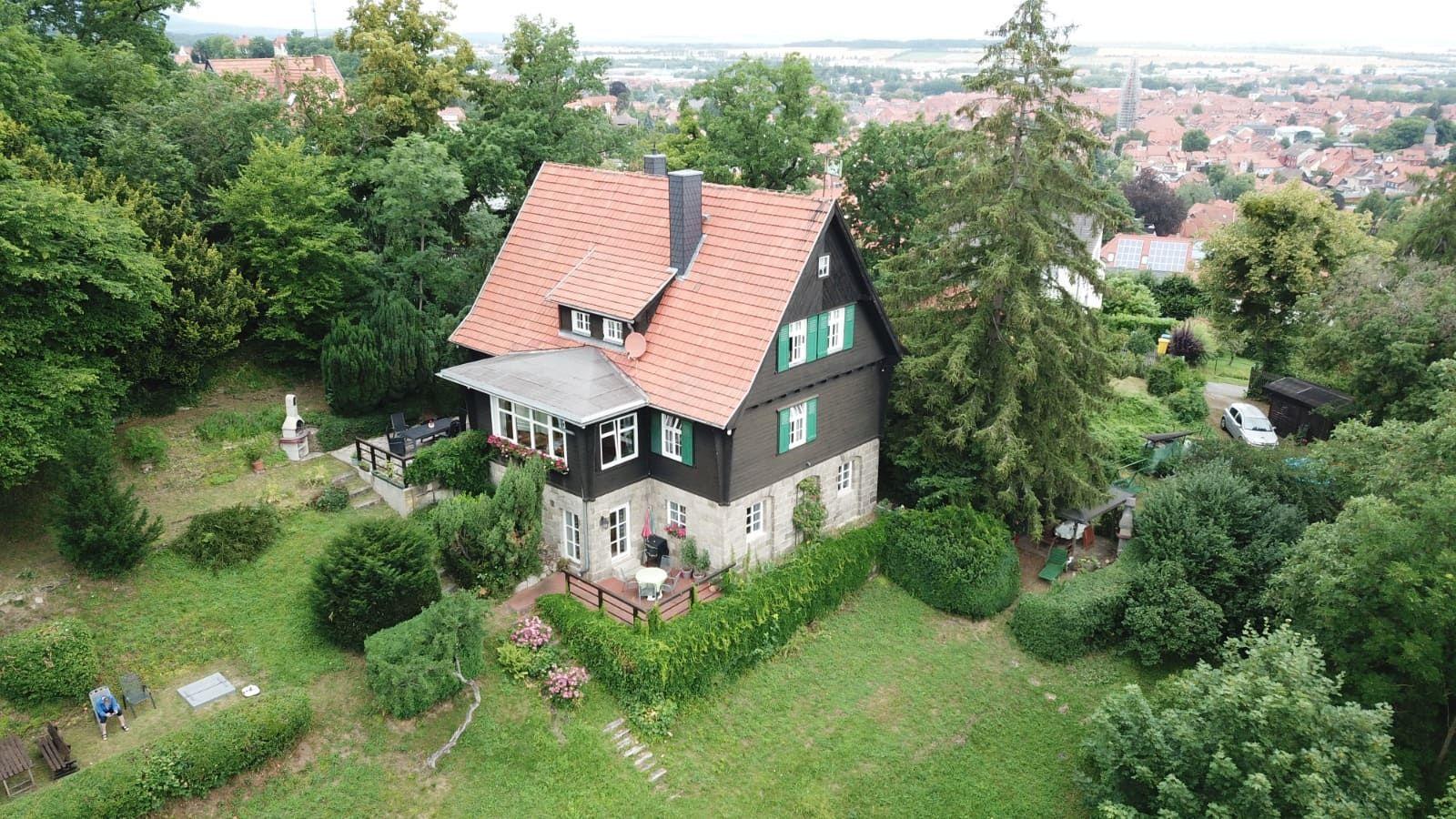 Haus mit rotem Dach, grüner Umgebung und Blick auf die Stadt
