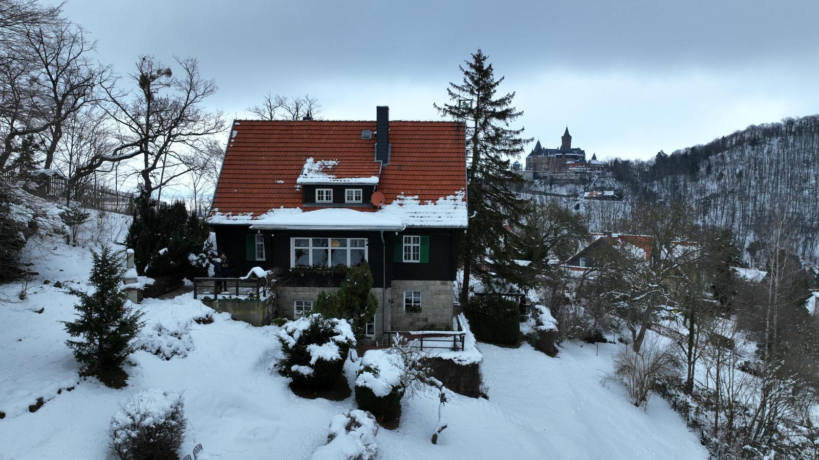Schneebedecktes Haus mit rotem Dach und Blick auf Schlossberg.