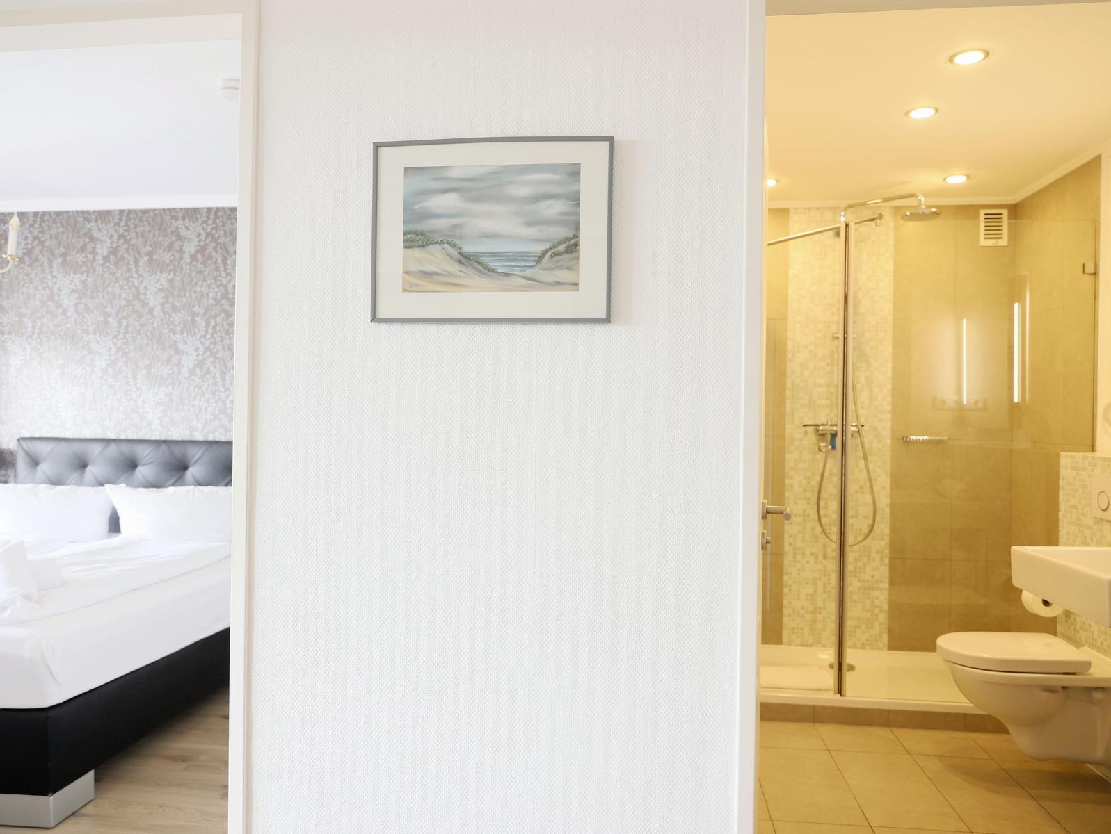 Schlafzimmer mit Bett und Badezimmer mit Dusche und Toilette