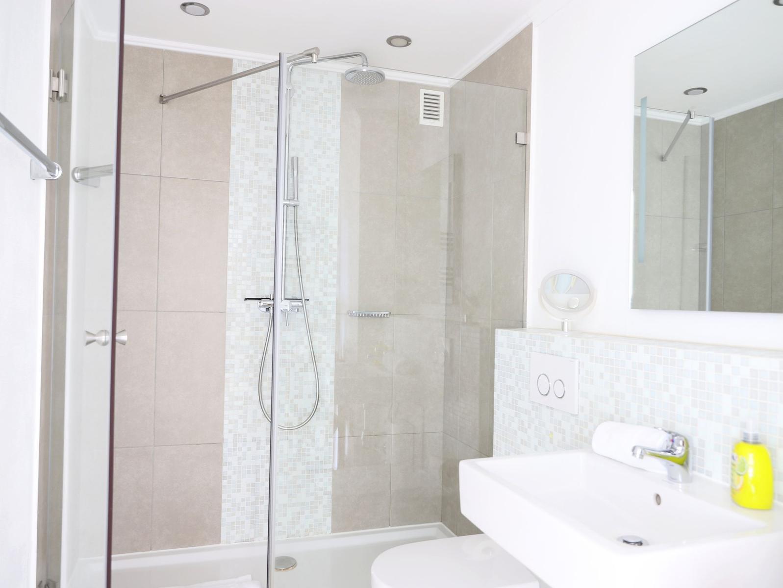 Badezimmer mit Dusche, Waschbecken und Spiegel