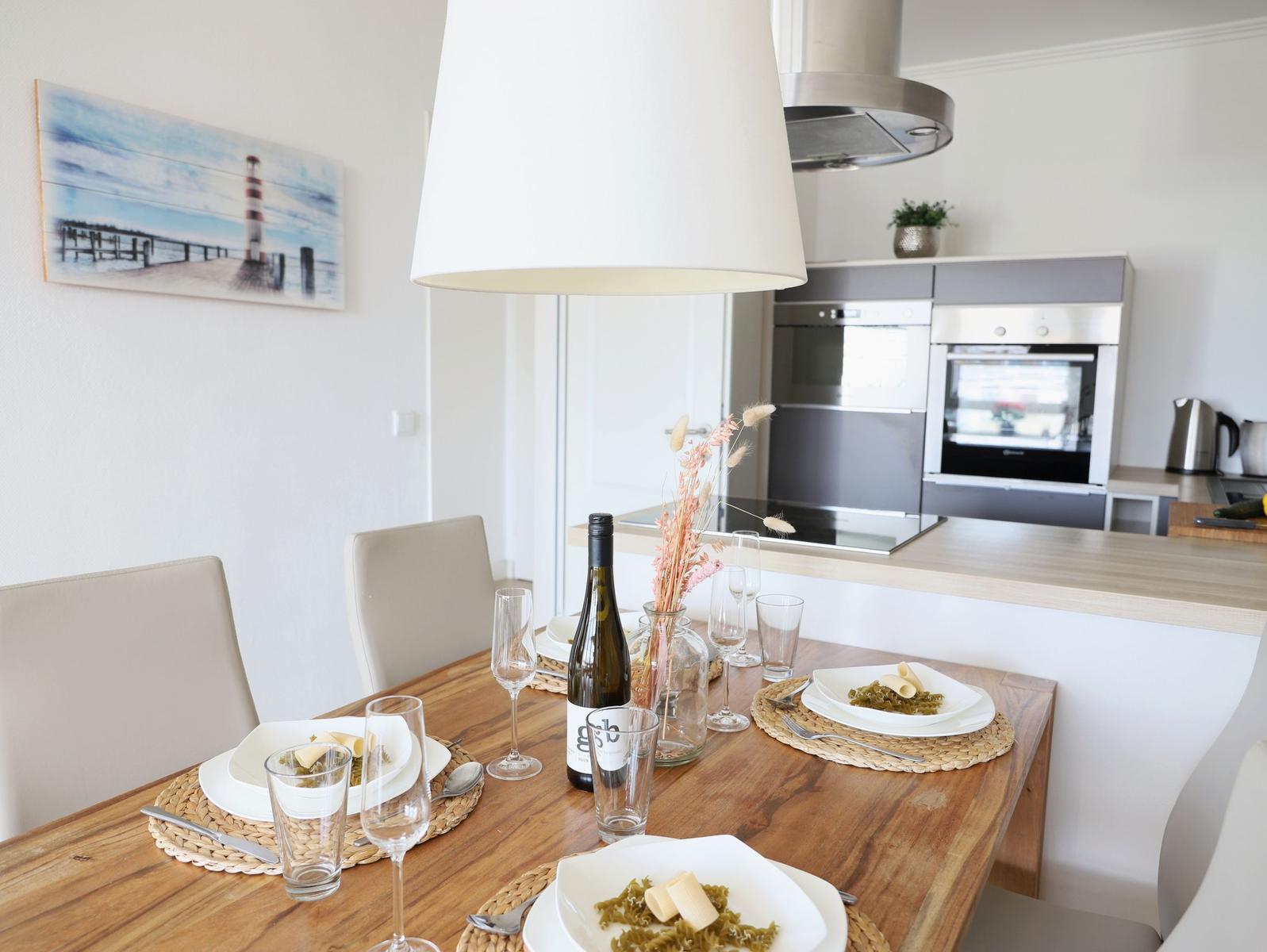 Essbereich mit Tisch, Stühlen und Küchenzeile im Hintergrund.