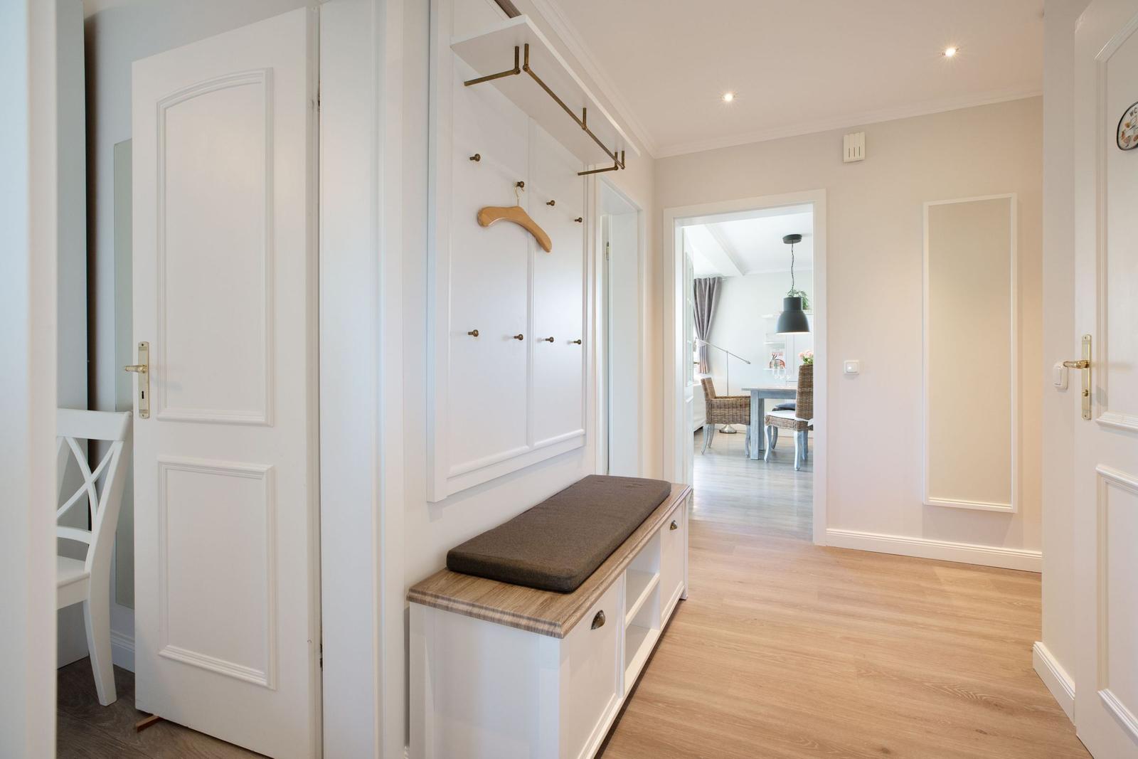 Eingangsbereich mit Garderobe, Sitzbank und Blick in Esszimmer.