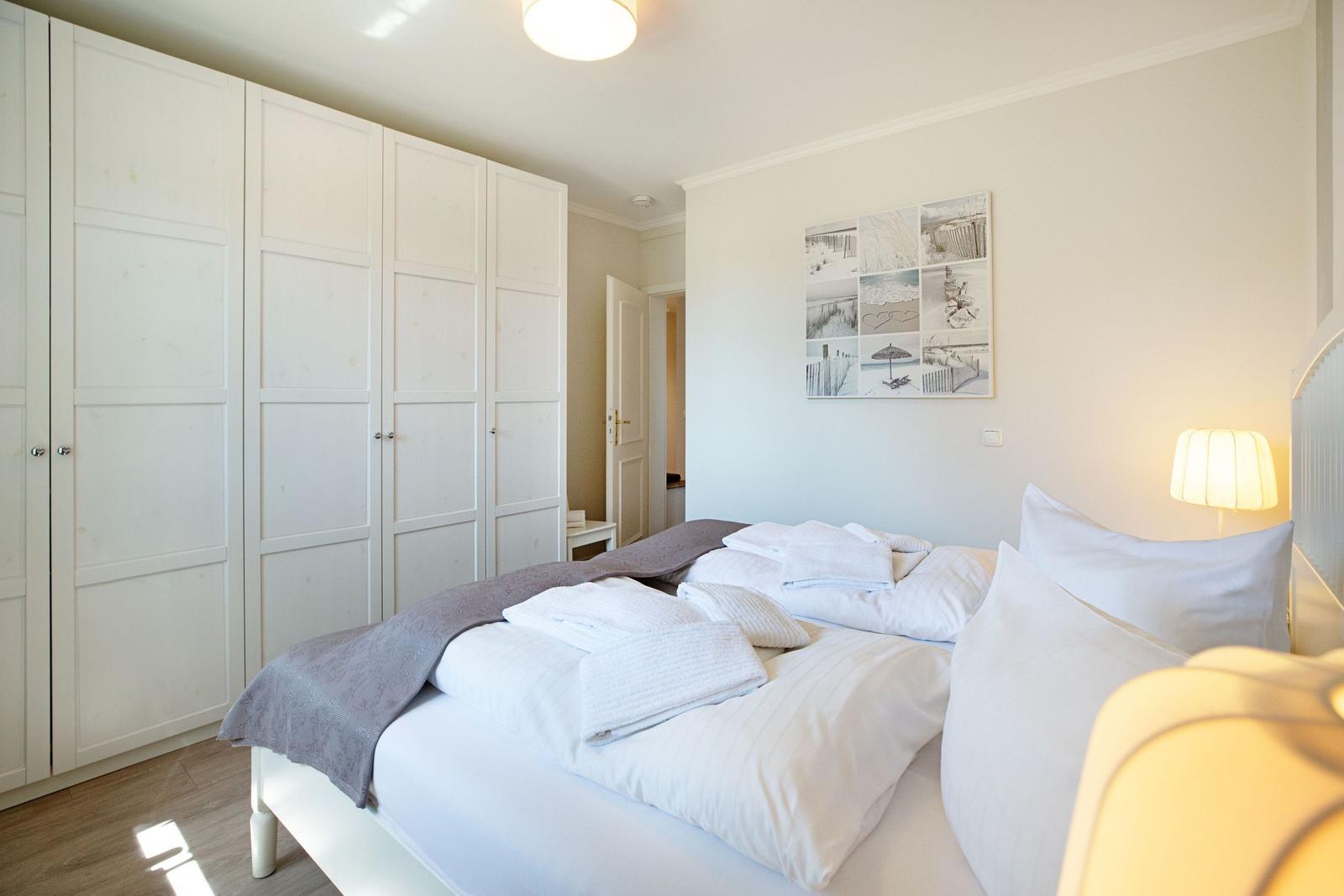 Schlafzimmer mit Bett, Kleiderschrank und Wandbild.