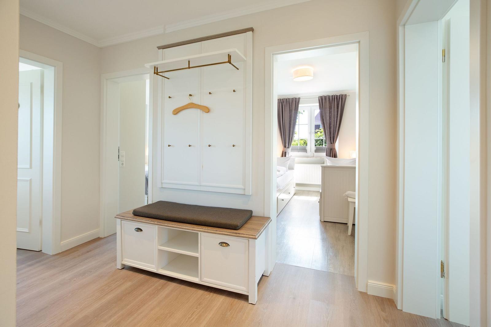 Eingangsbereich mit Kleiderschrank und Sitzbank. Durchgang zu Schlafzimmer mit Fenster.