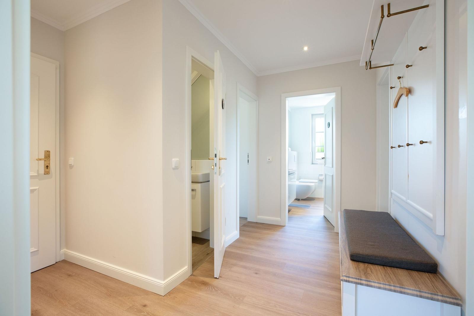 Flur mit Holzboden, Garderobe und Blick in Bad und WC.