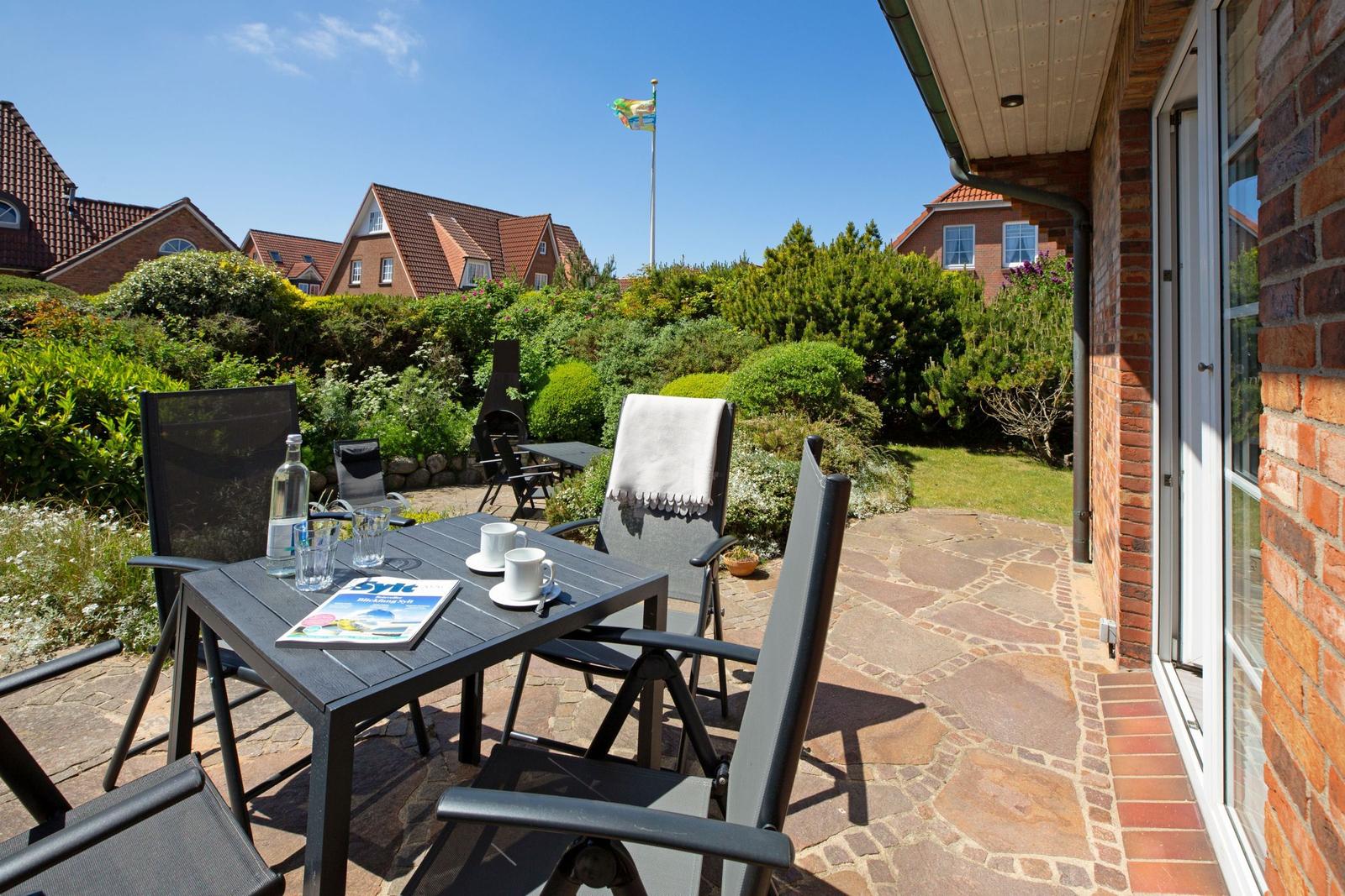 Terrasse mit Tisch und Stühlen, Blick auf Garten und Nachbarhäuser.