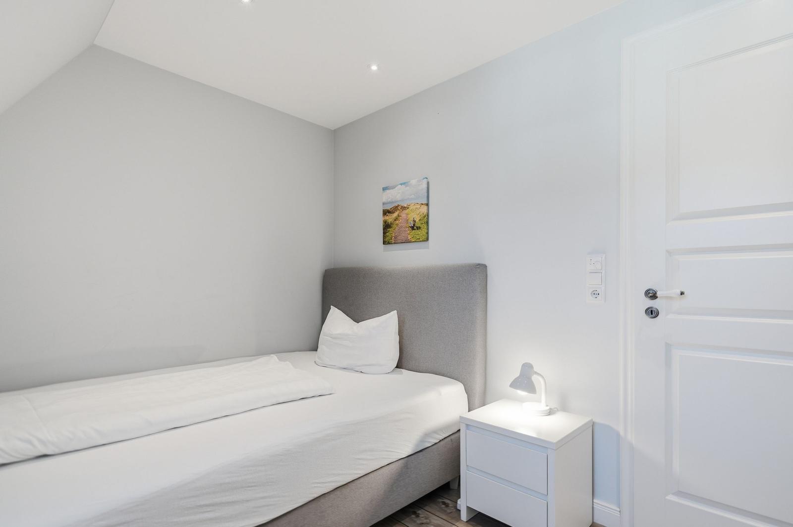 Schlafzimmer mit Bett, Nachttisch und Wandbild.
