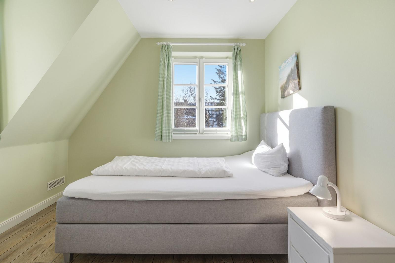 Schlafzimmer mit Dachschräge, Fenster und Bett.