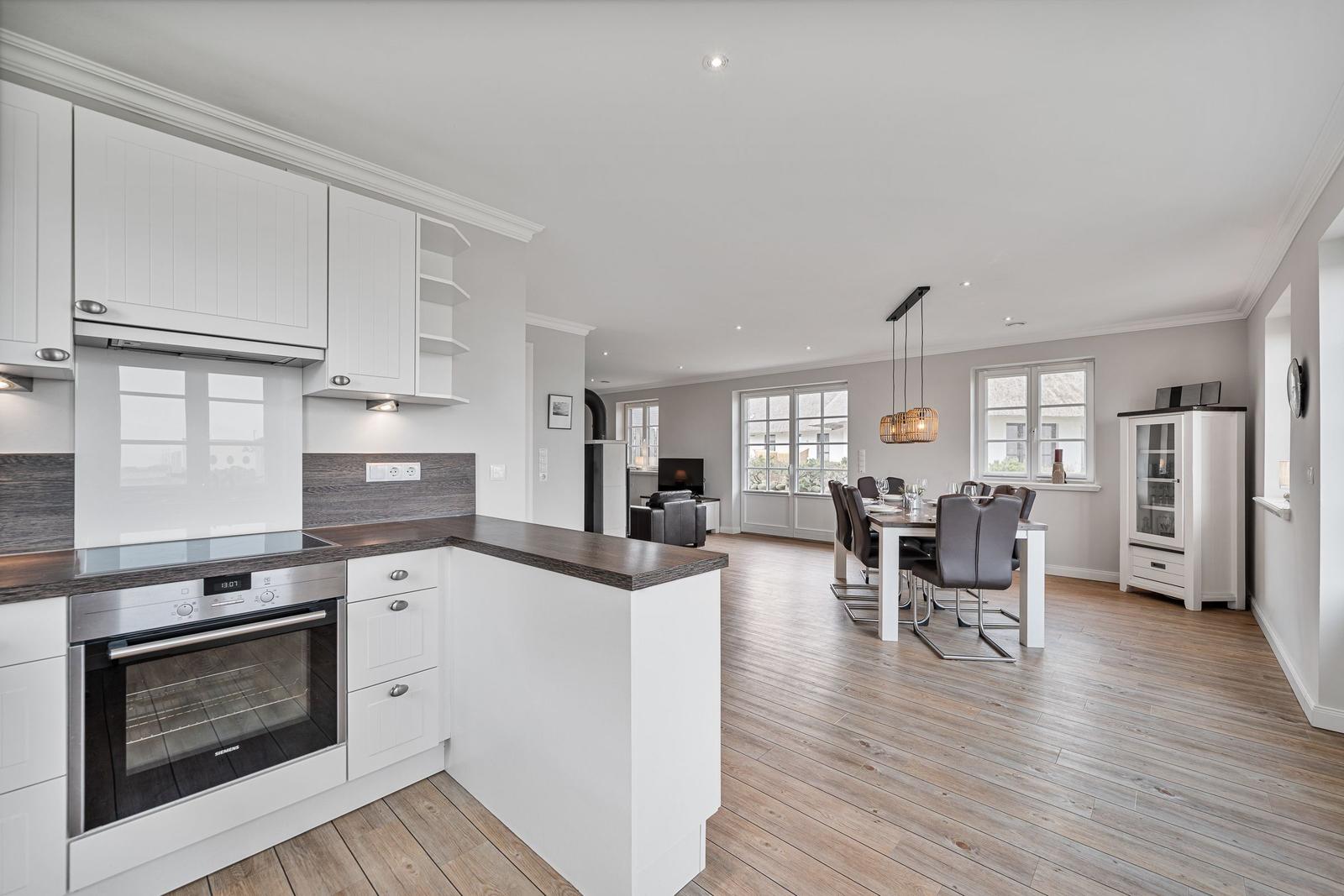 Moderne Küche mit Essbereich und Wohnzimmer im Hintergrund.