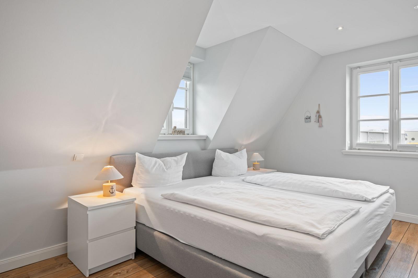 Schlafzimmer mit Doppelbett, zwei Nachttischen und Fenstern mit Blick.