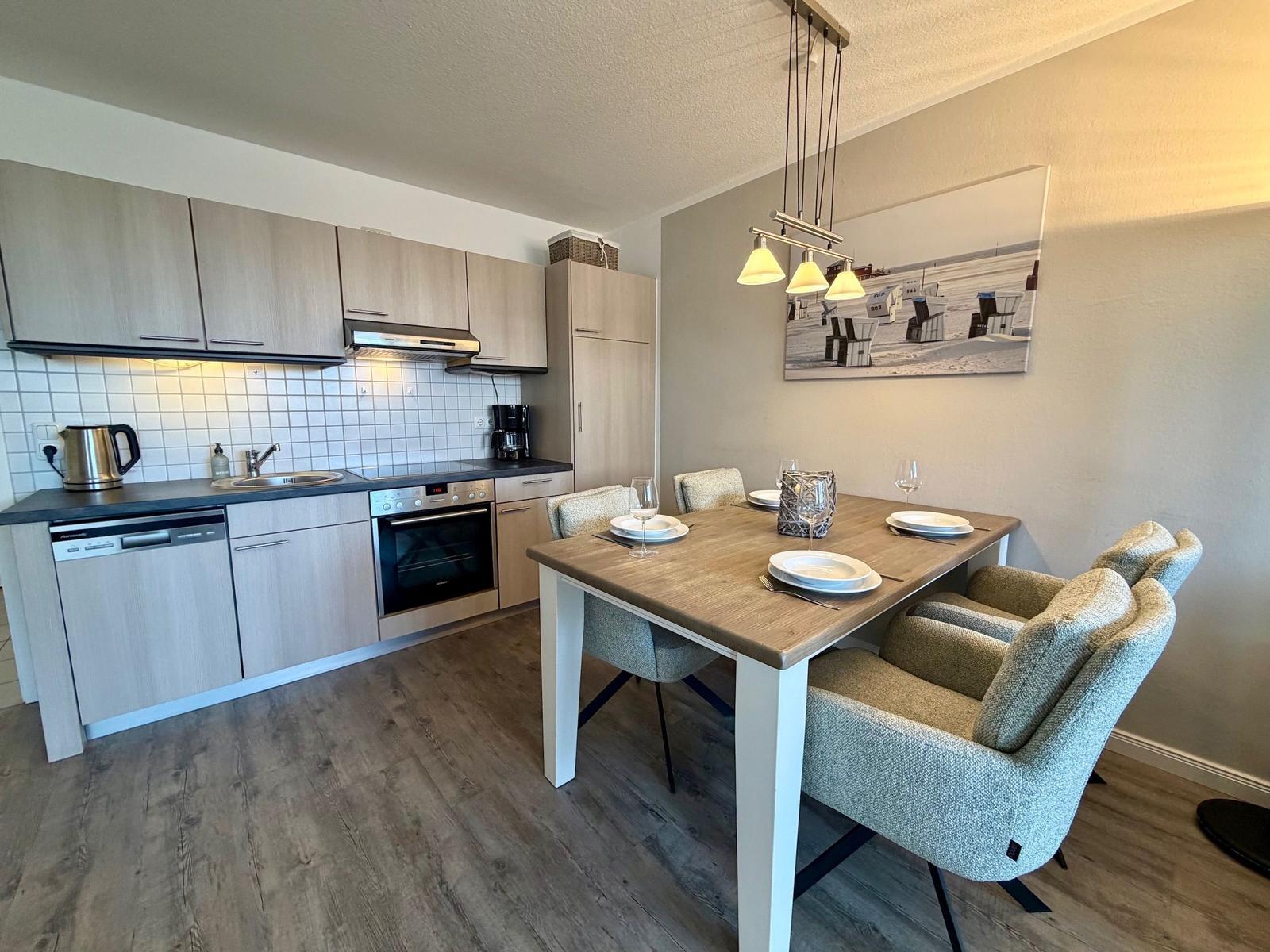Küche mit Essbereich, Holztisch, Stühle, Küchenschränke und Wandbild.