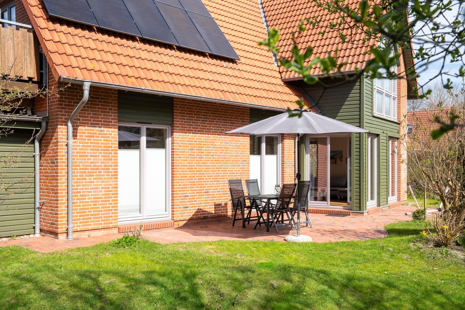 Haus mit Terrasse, Garten und Solaranlage. Außentisch mit Sonnenschutz.