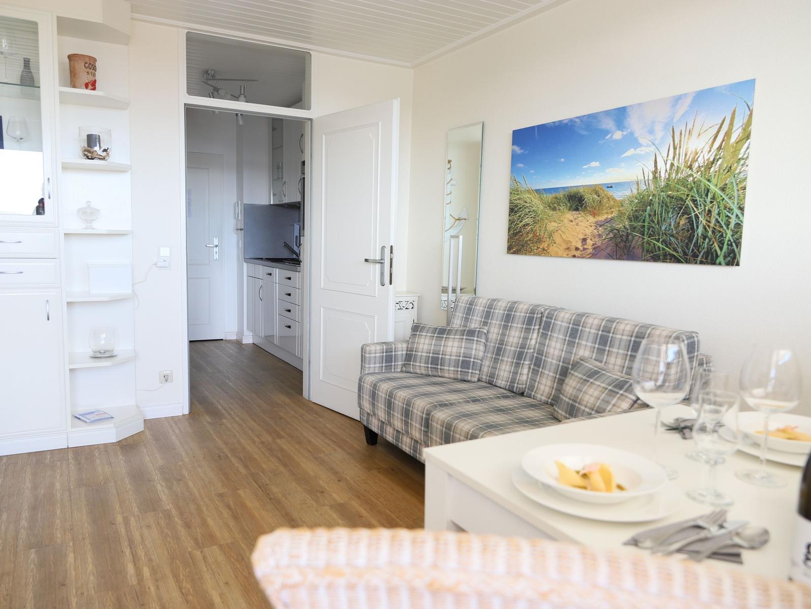 Wohnbereich mit Sofa, Esstisch und Blick in die Küche.