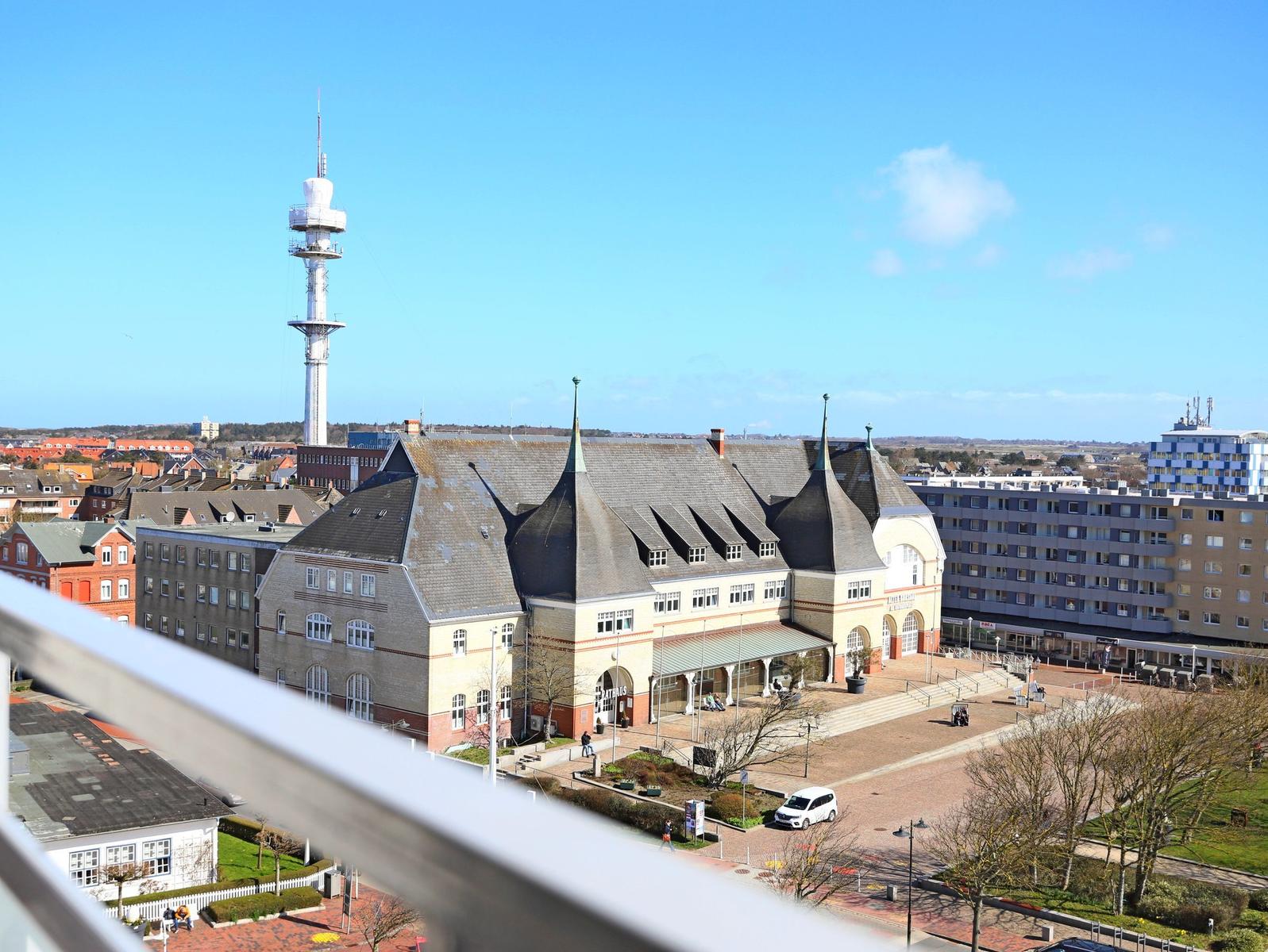 Blick auf historisches Gebäude mit spitzen Dächern und Fernsehturm im Hintergrund.