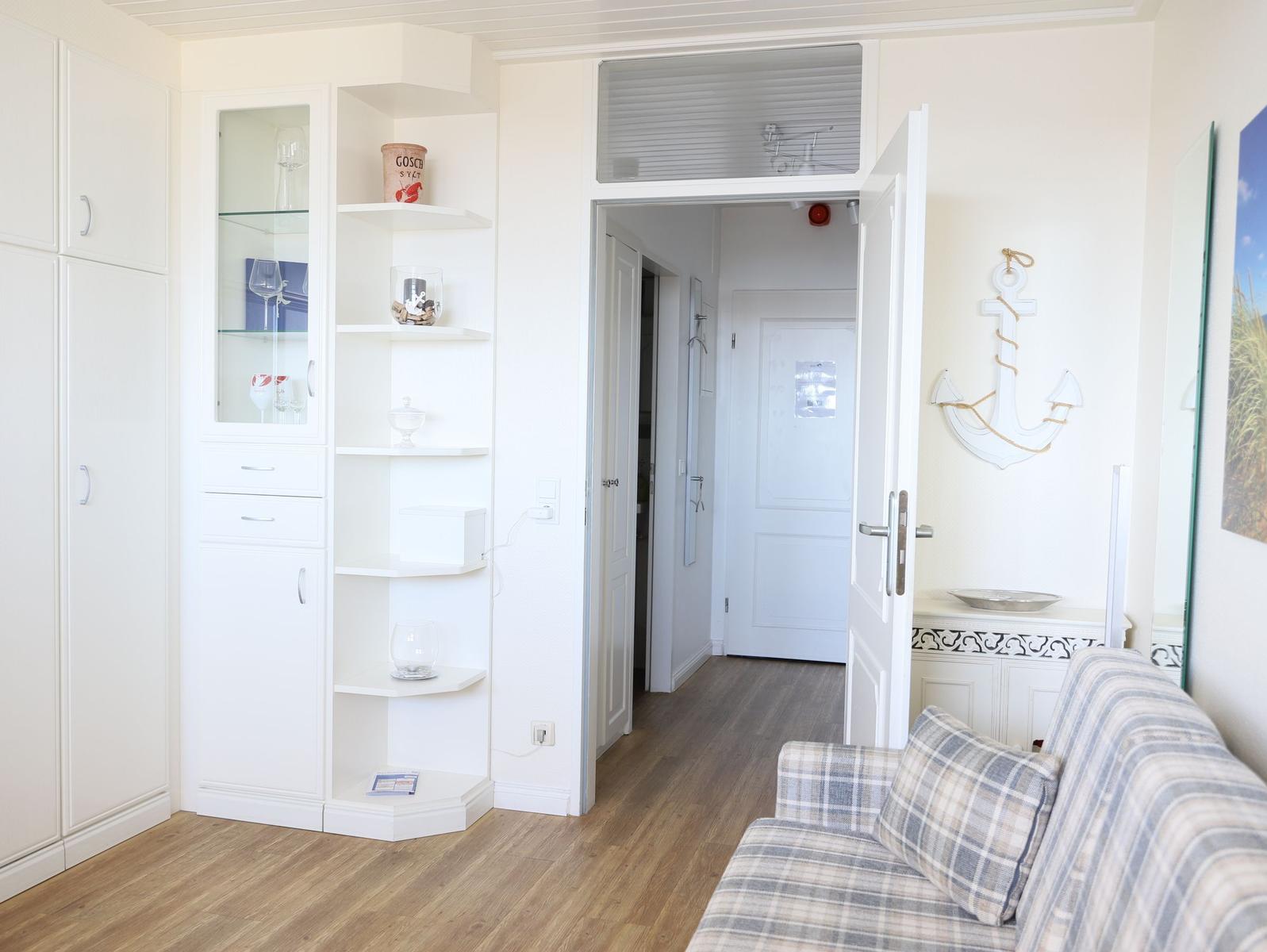 Wohnzimmer mit Sofa, weißen Schränken und Anker-Dekoration an der Wand.