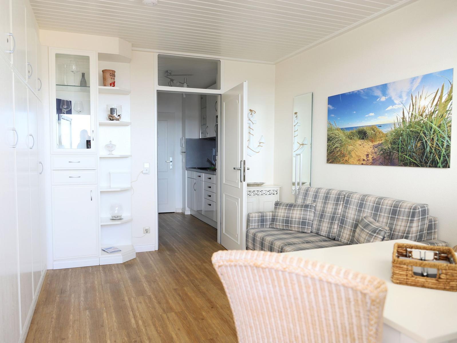Wohnzimmer mit Sofa, Küchenbereich und Wandbild
