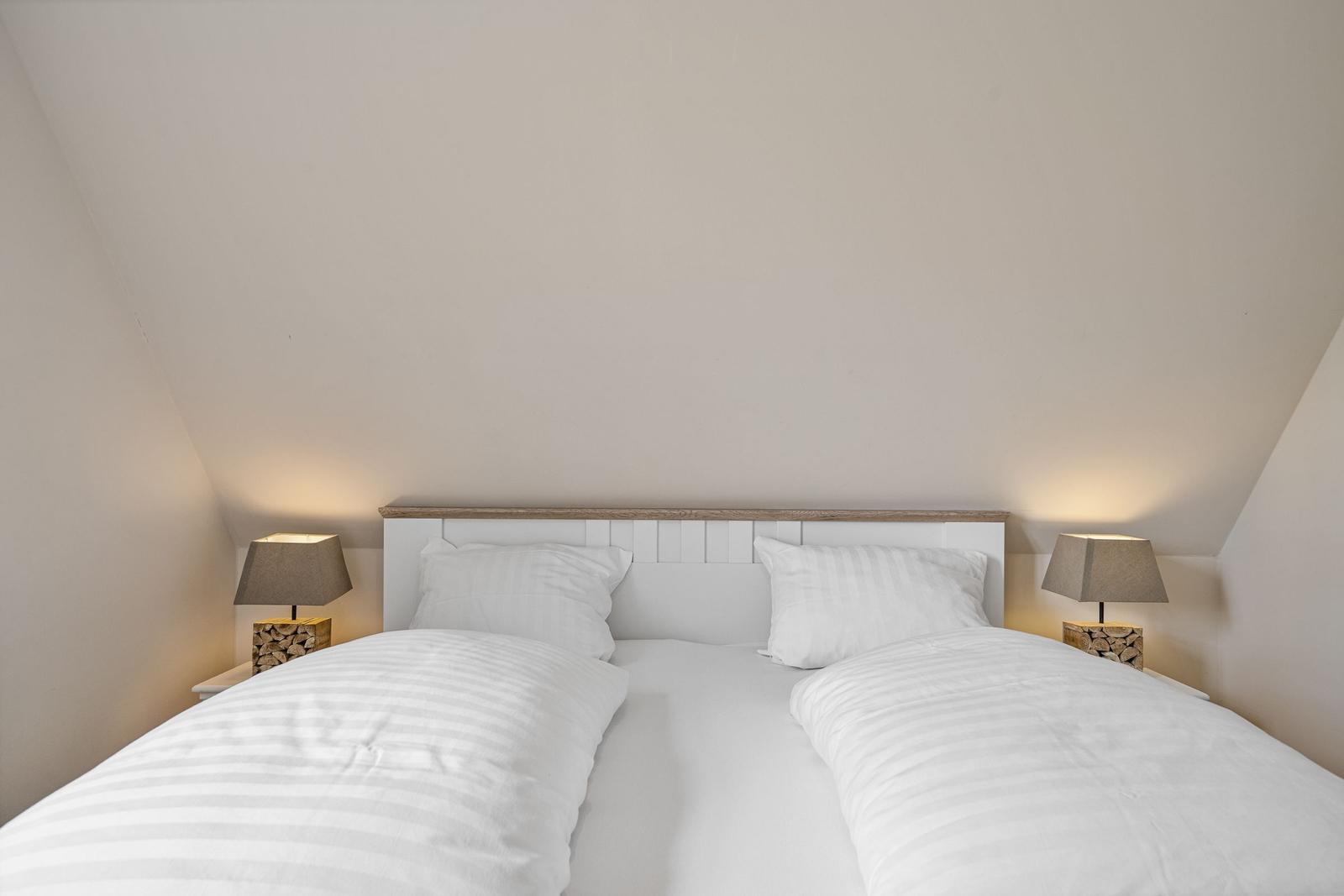 Ein Doppelbett mit weißen Bettwäsche und zwei Nachttischen mit Lampen.