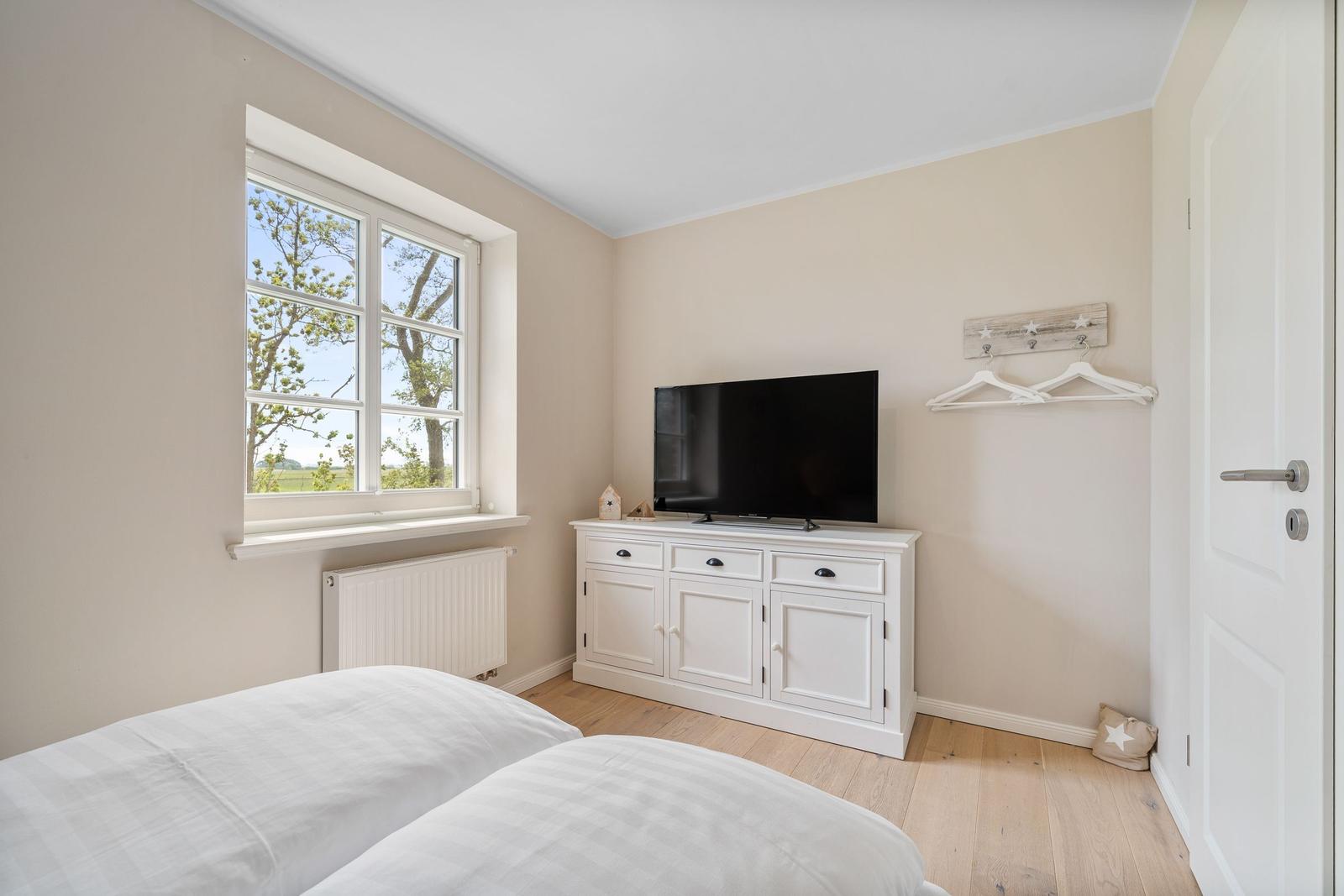 Schlafzimmer mit Fenster, TV-Schrank und Bett.