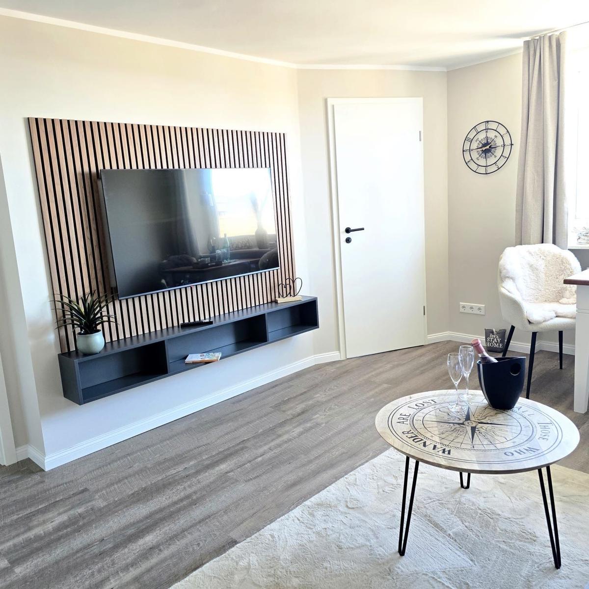 Living room with TV on wood wall, coffee table with compass design, and seating area.