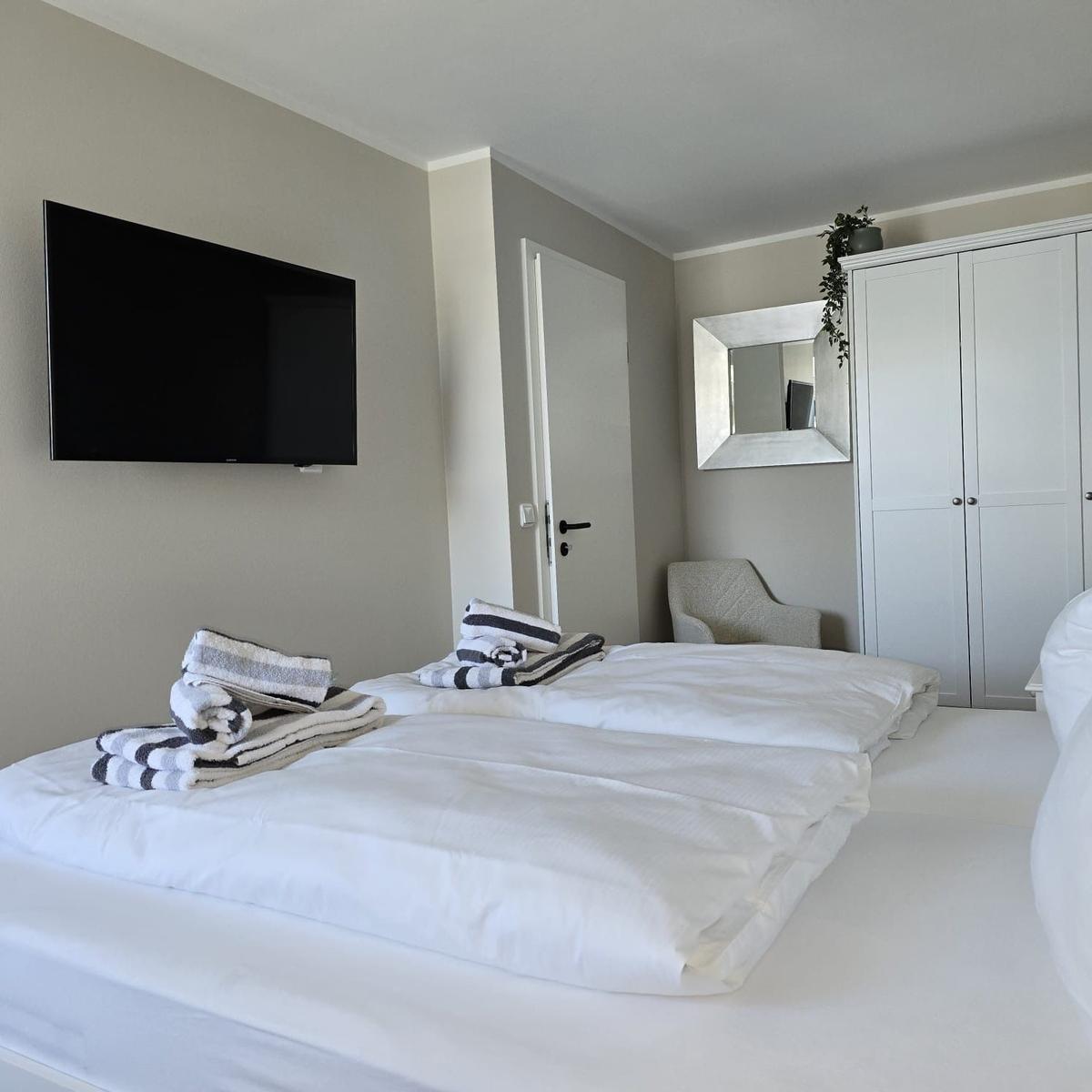 Room with double bed, TV, wardrobe, and mirror.