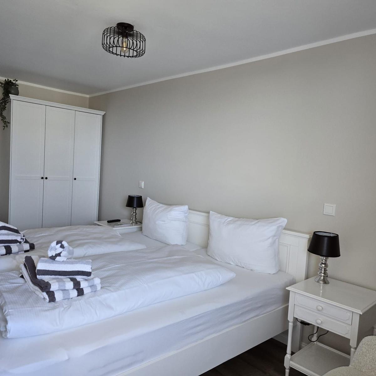 Bedroom with double bed, white nightstands, and wardrobe.