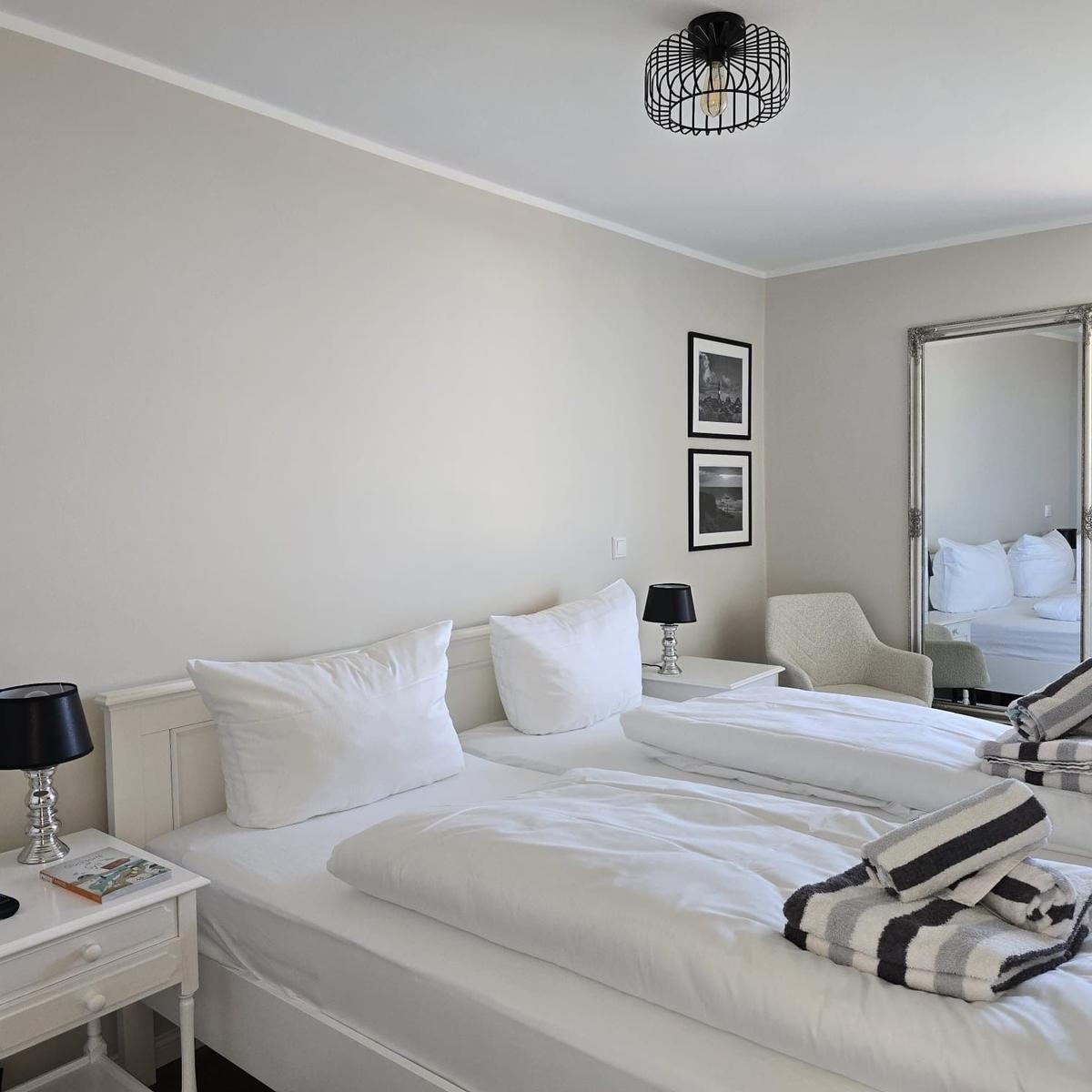 Room with double bed, nightstand, mirror, and blankets