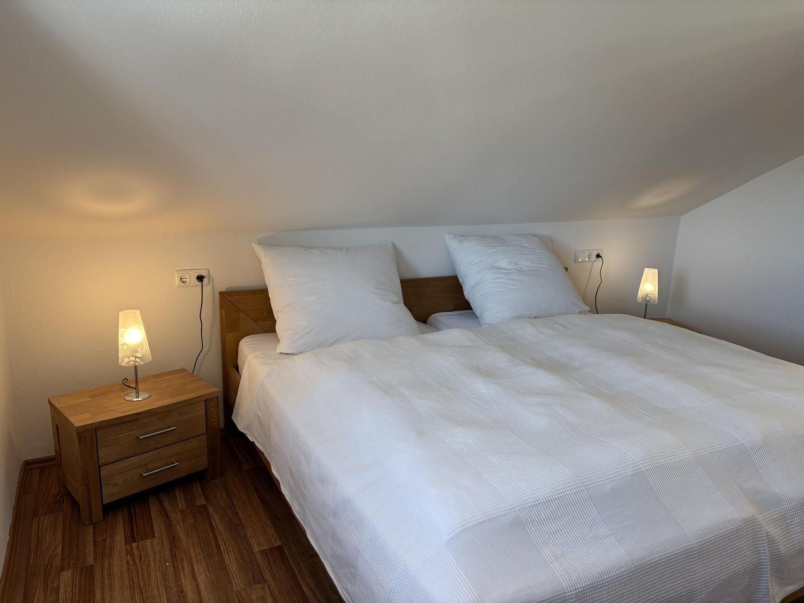 Schlafzimmer mit Doppelbett, zwei Nachttischen und Lampen an der Wand.