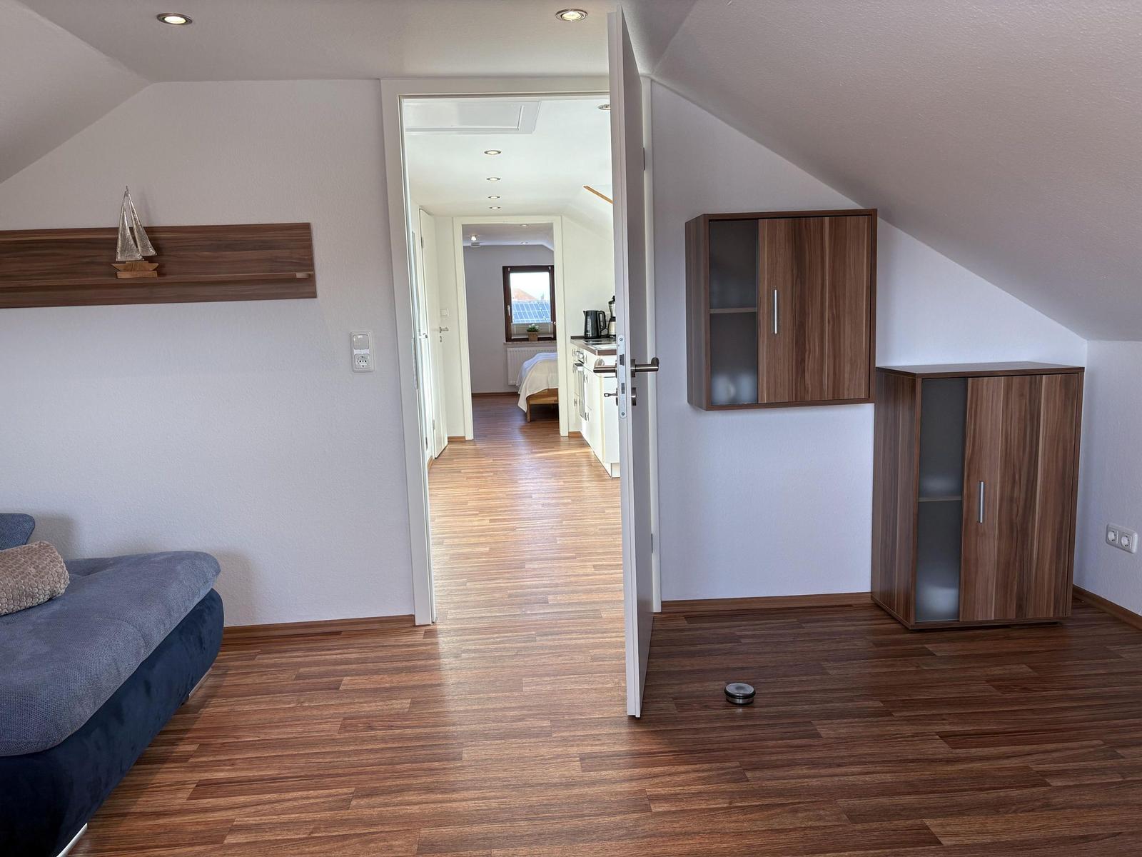 Schlafzimmer mit Holzboden und Blick in die Küche