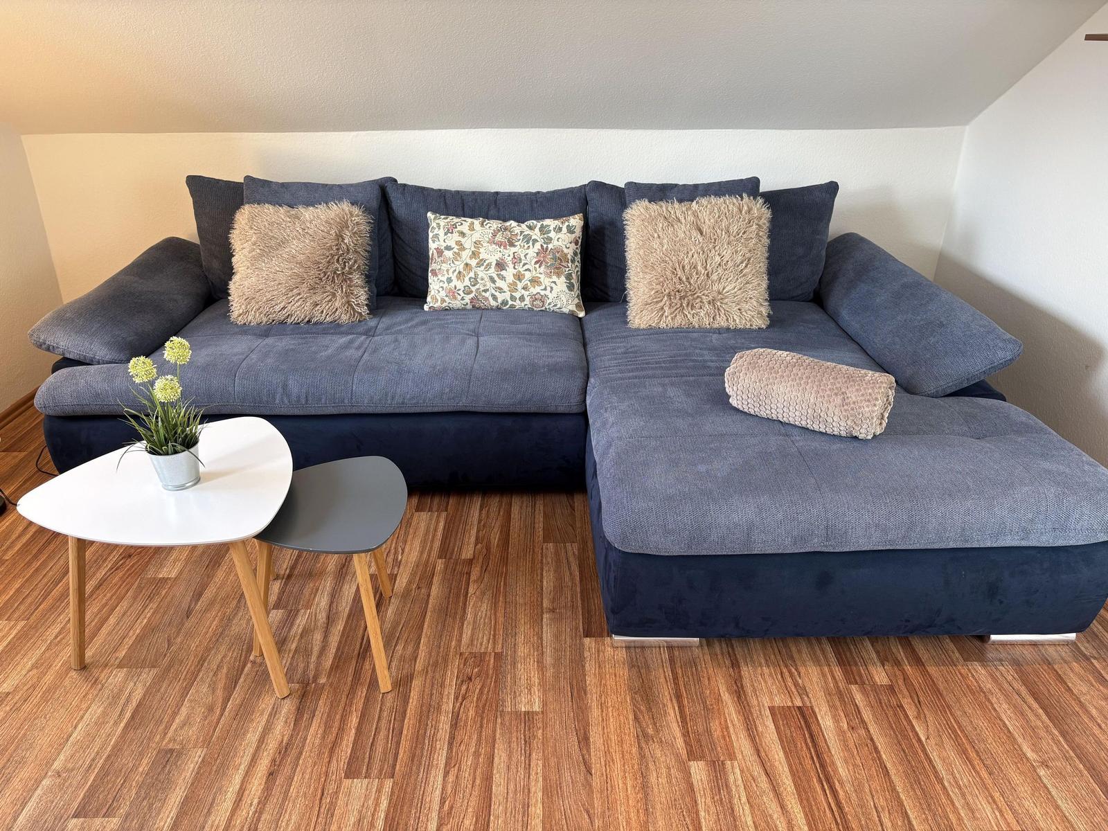 Ein graues Sofa mit Kissen und einem Beistelltisch auf Holzboden.