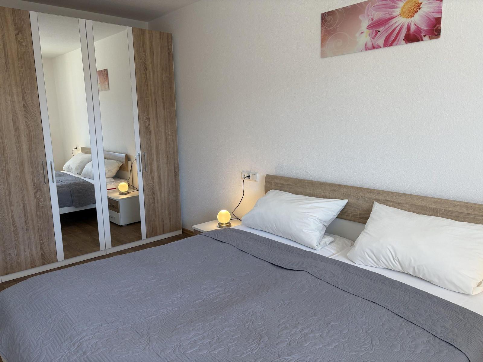 Schlafzimmer mit Doppelbett, Spiegelschrank und Wandbild