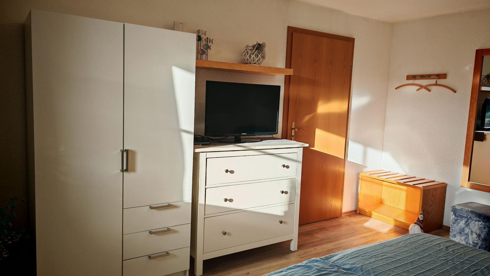 Schlafzimmer mit Kleiderschrank, Schreibtisch und Fernseher.