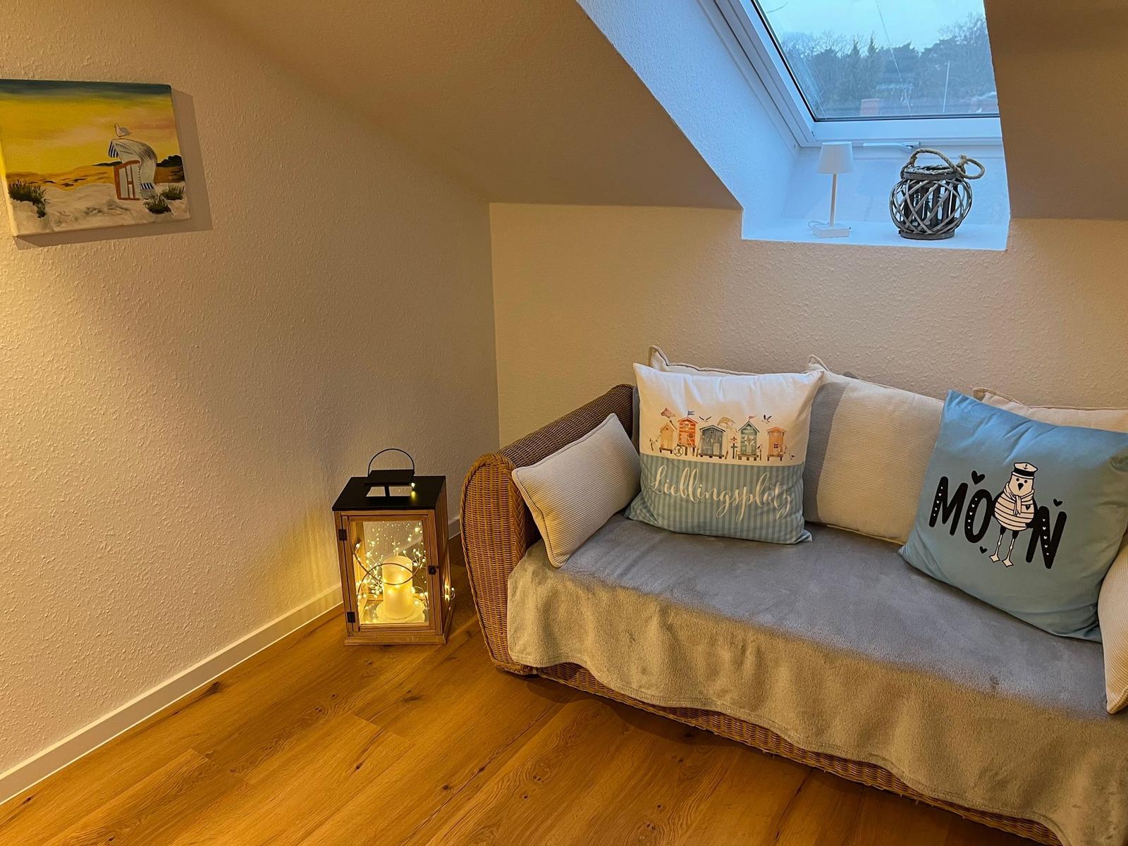 Wohnbereich mit Sofa, Fenster und dekorativen Kissen.