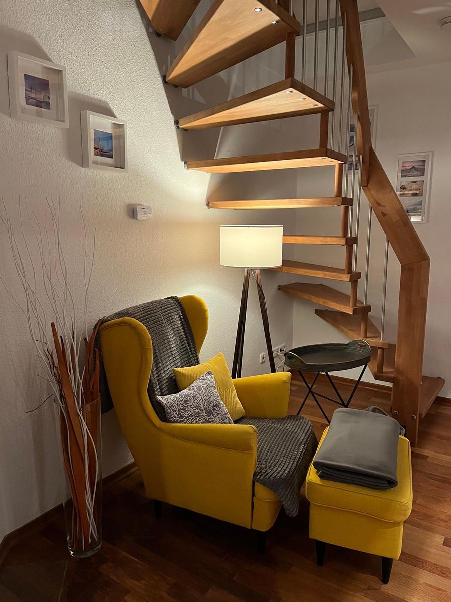 Gelber Sessel mit Kissen und Decke neben Holztreppe