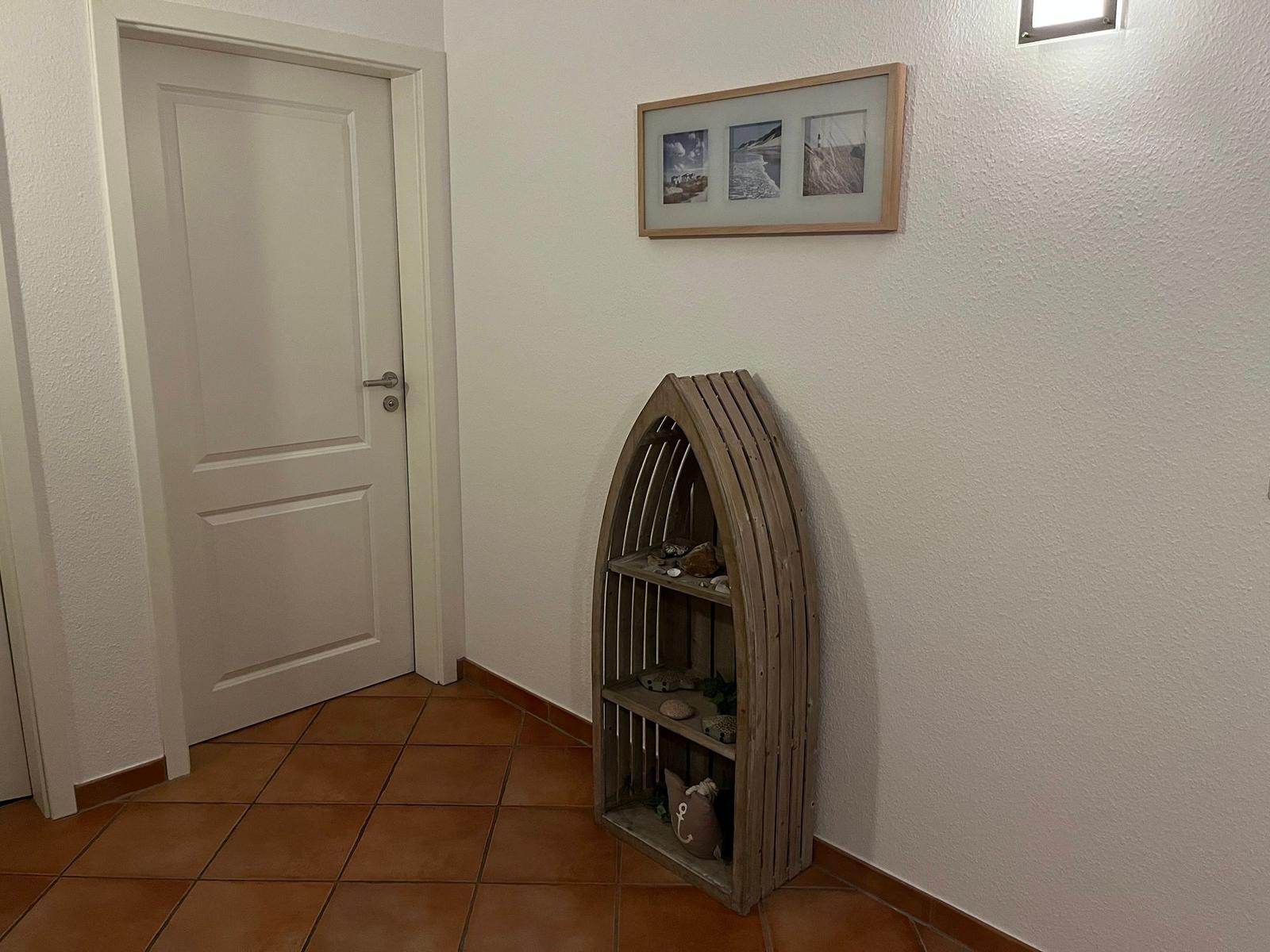 Eingangsbereich mit Tür, Wandbild und hölzernem Regal in Bootsform.