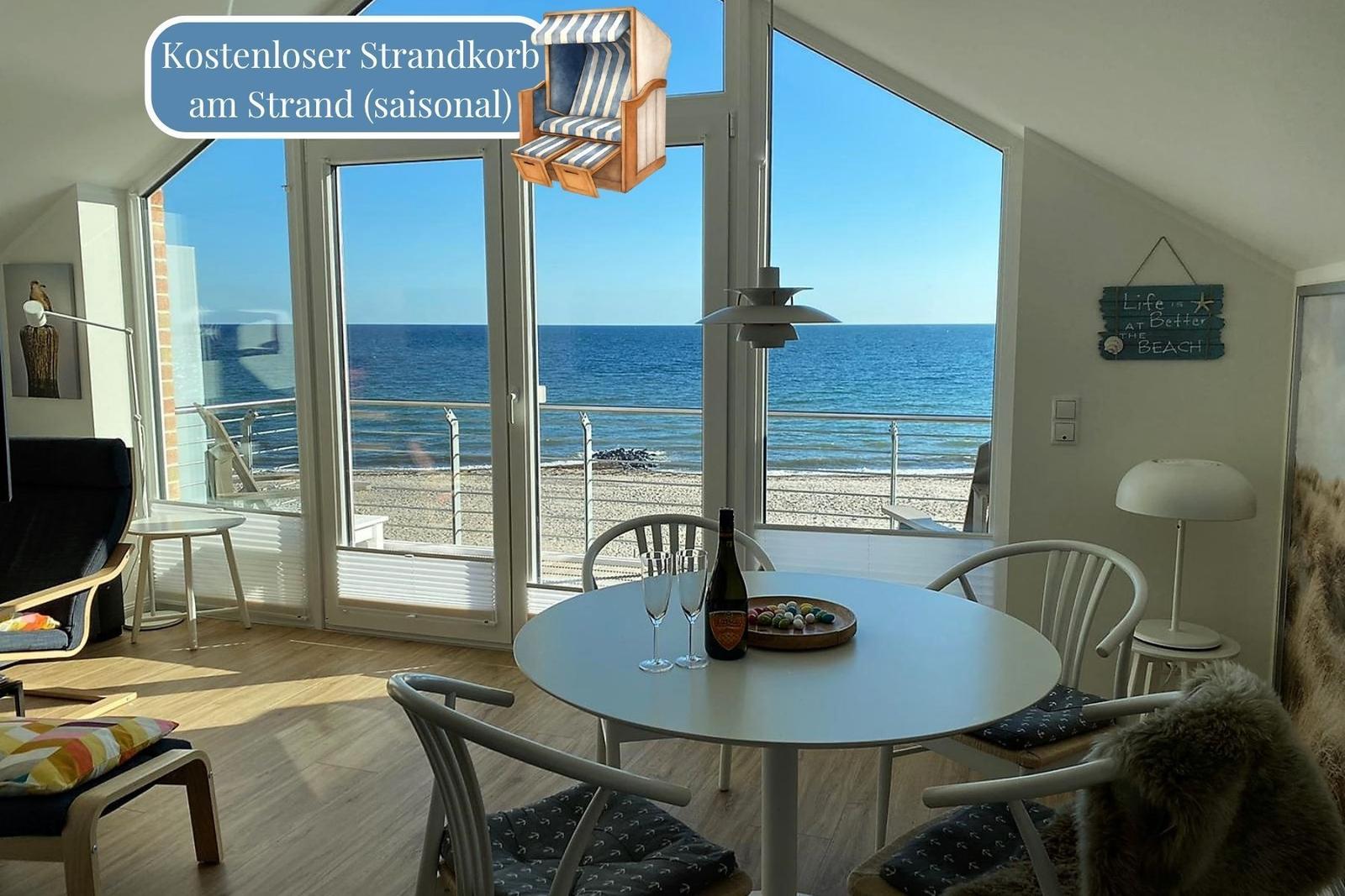 Küche mit Tisch und Stühlen, Blick auf den Strand durch große Fenster.