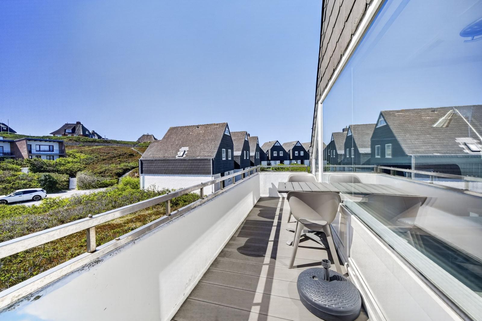 Terrasse mit Tisch und Stühlen, Blick auf Häuser und Grünflächen.