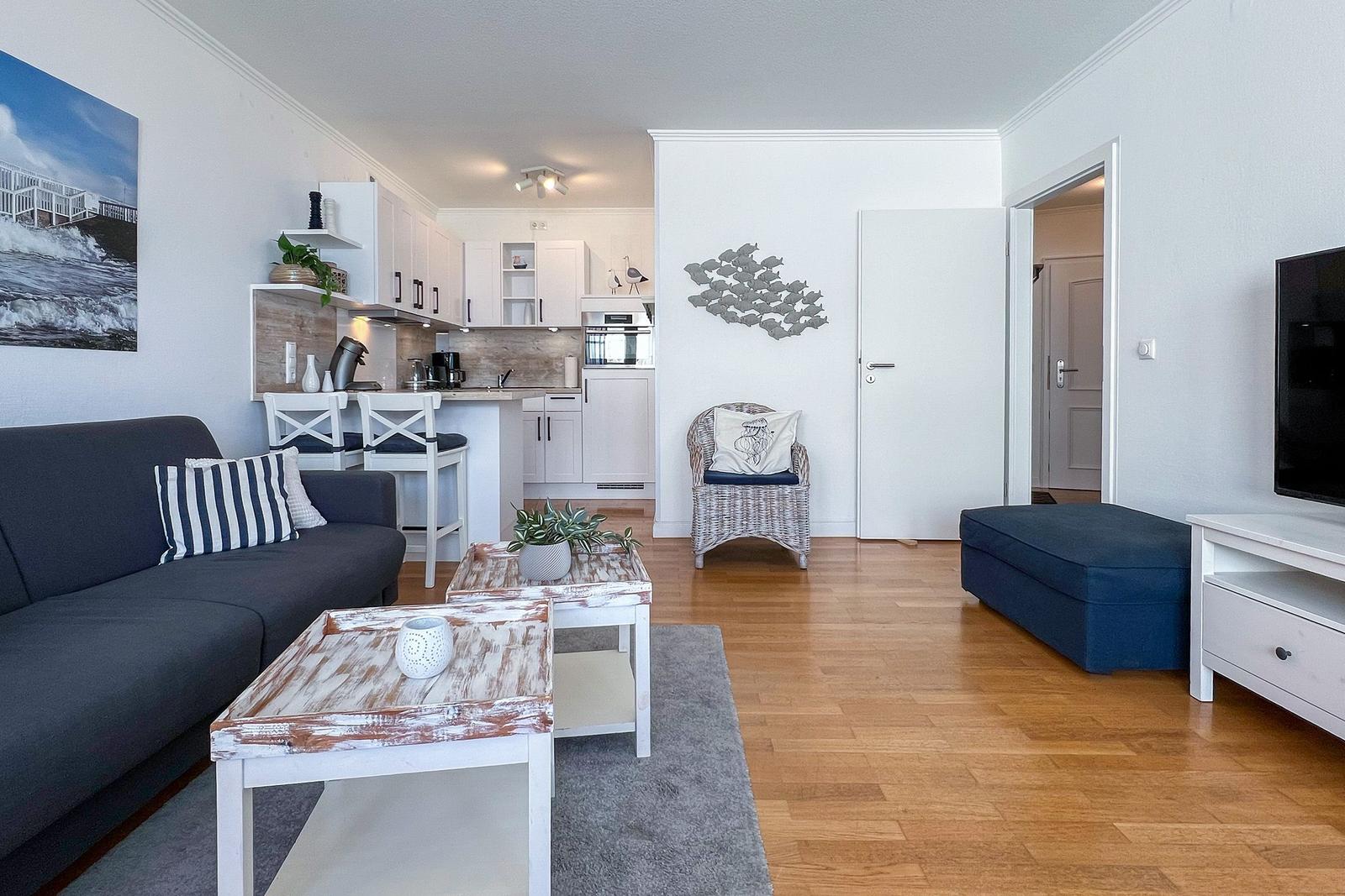 Wohnzimmer mit Küchenbereich, Sofa, Couchtisch und Fernseher.