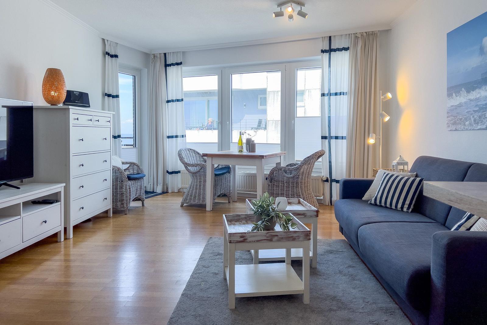 Wohnzimmer mit Sofa, Esstisch und Blick auf Balkon.