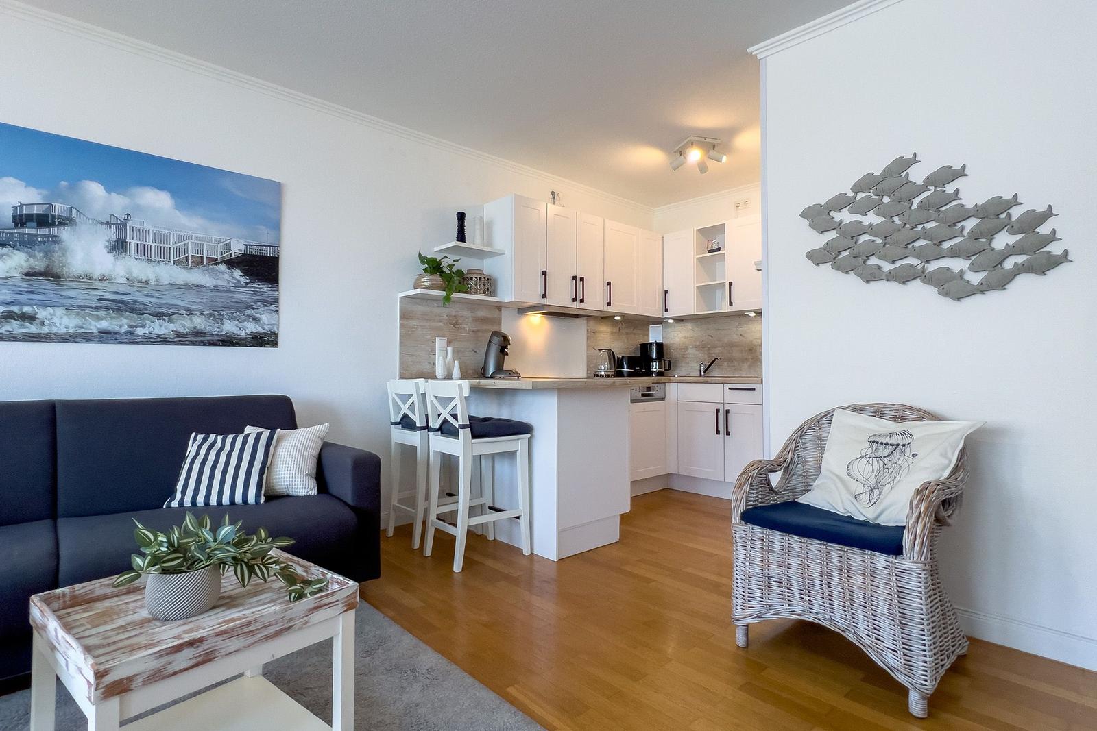 Wohn- und Küchenbereich mit Sofa, Stuhl und Küchenzeile.