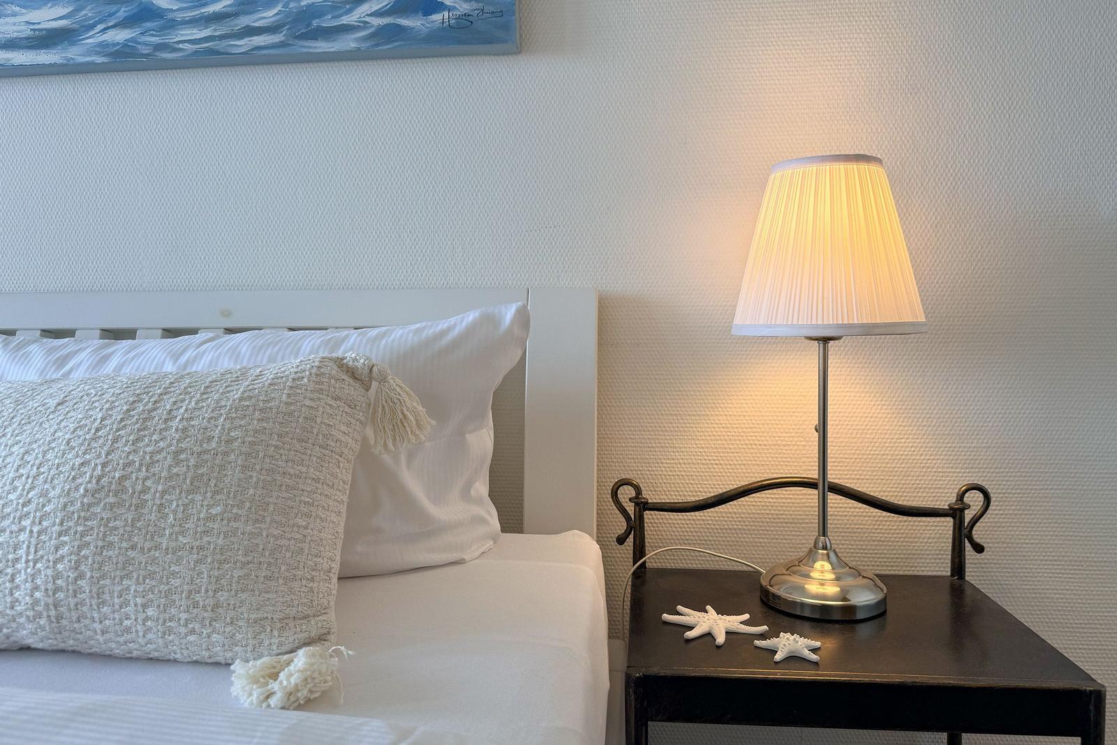 Bettkopfteil mit Kissen, Nachttisch mit Lampe und Seestern