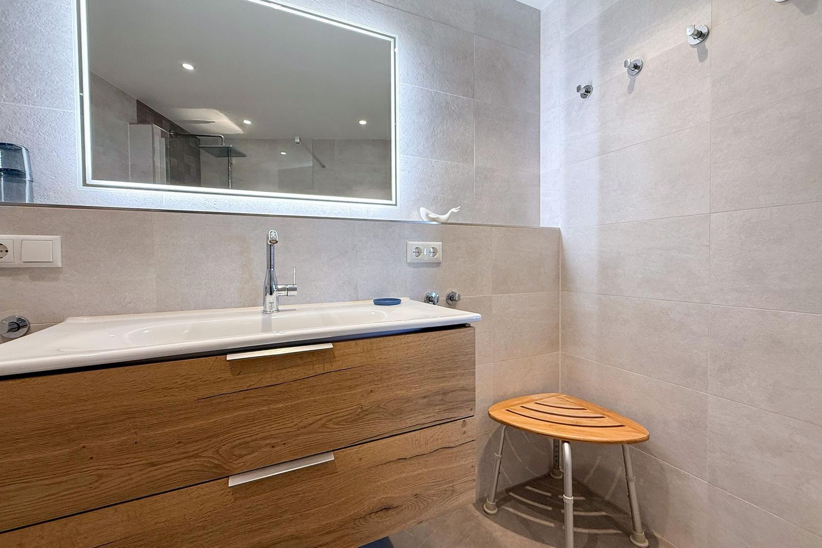 Bad mit Waschbecken, Spiegelschrank und Duschstuhl