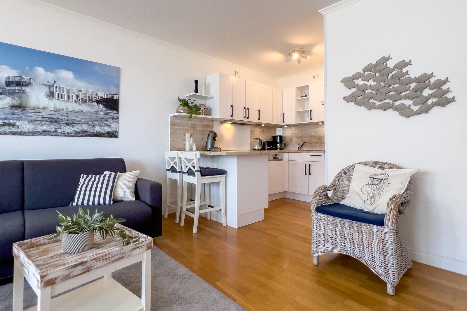 Wohnbereich mit Küchenzeile, Sofa, Sessel und Wandbild an der Wand.