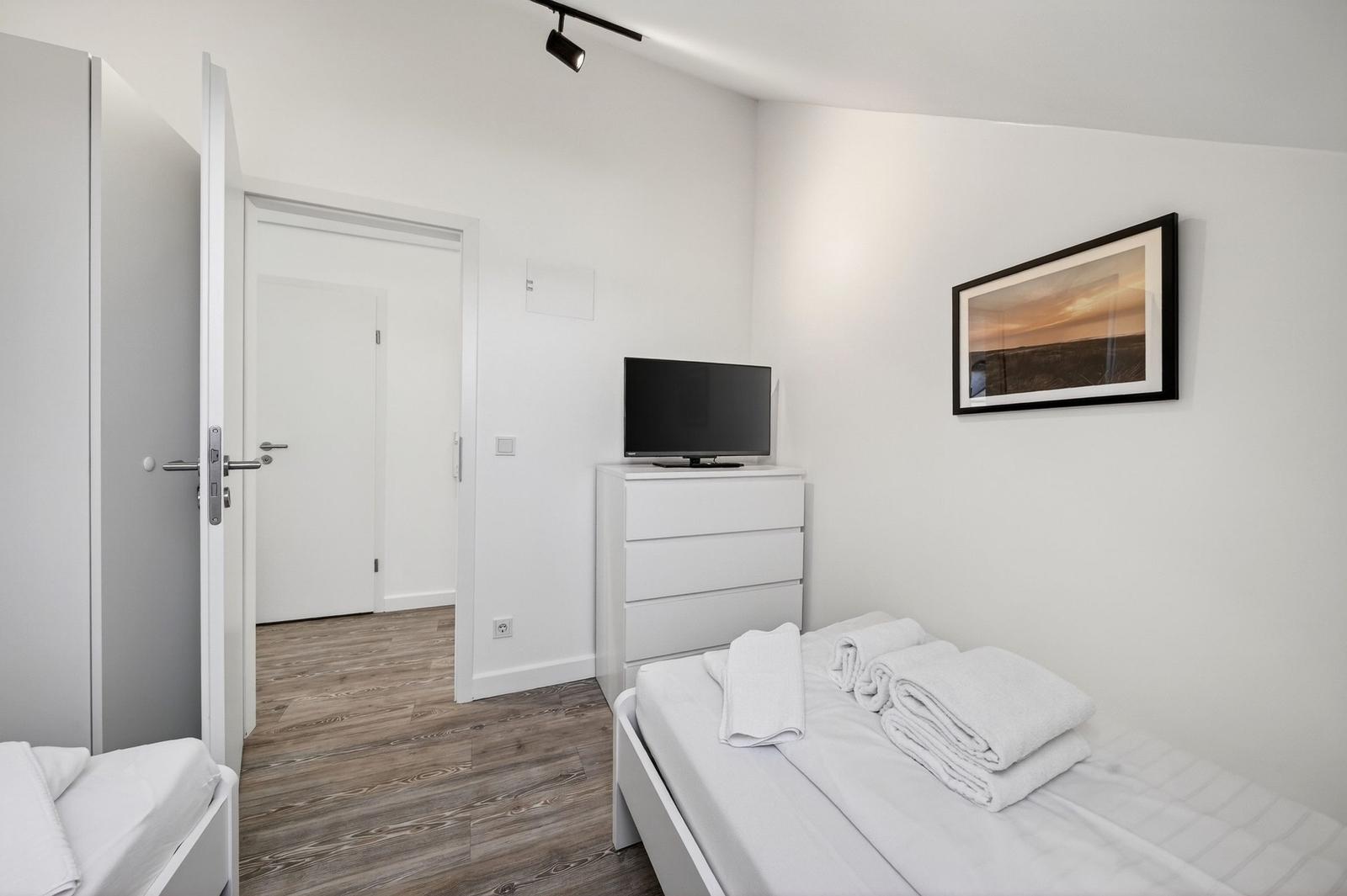 Schlafzimmer mit Bett, Kleiderschrank und Fernseher auf Kommode