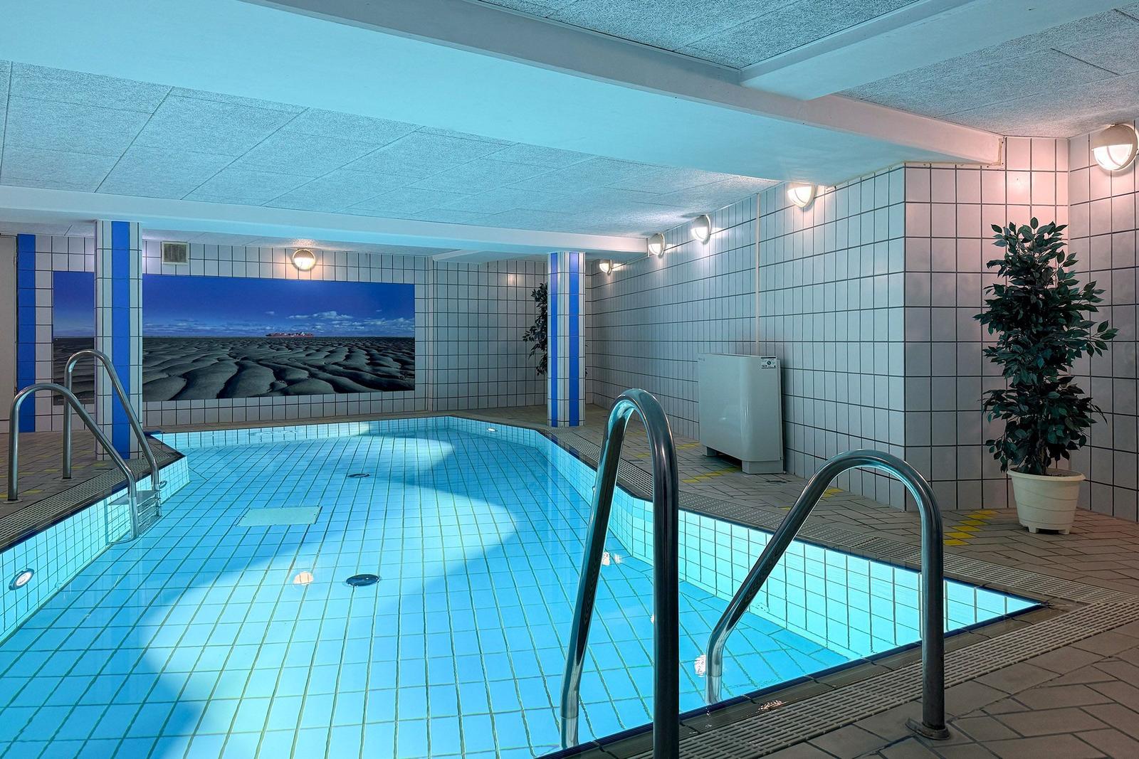 Innenpool mit blauen Fliesen, Metalltreppen und Wandbild