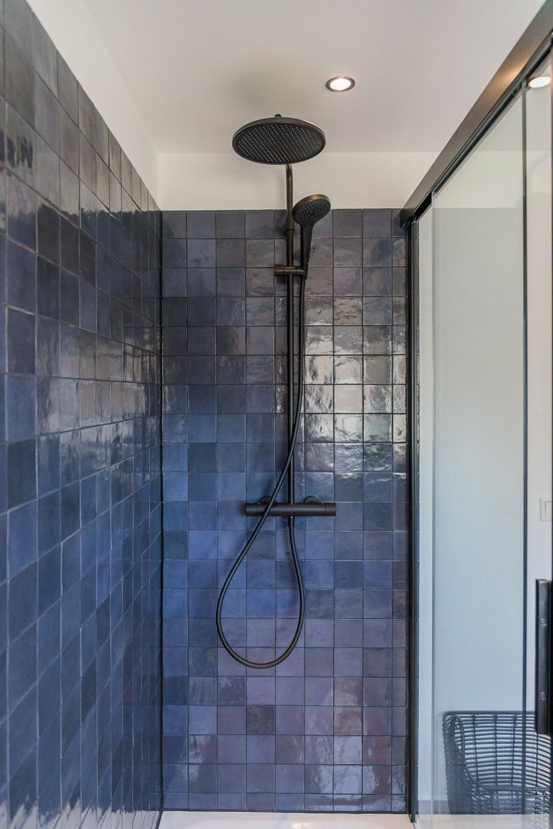 Shower with dark blue tiles and showerhead
