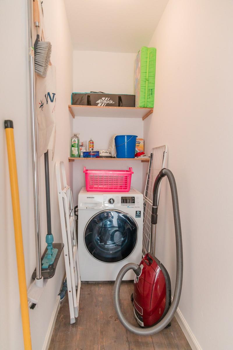 Washing machine, vacuum cleaner, and cleaning supplies in a narrow room.